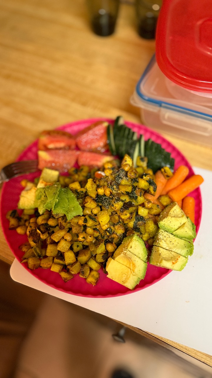 A colorful home-cooked plate with vegetables, avocado and a chickpea skillet